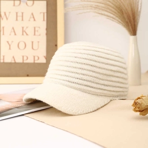 Detail of cream knit baseball cap with vertical ribbed texture and structured brim