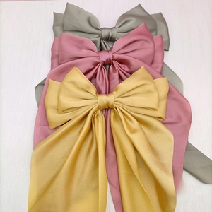 Detailed stack of multi-layered satin bow hair clips in gray, pink, and yellow colors
