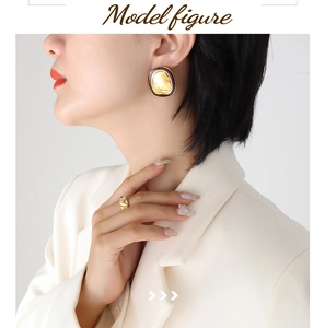 Detail of vintage gold textured earrings and twisted ring worn by a model