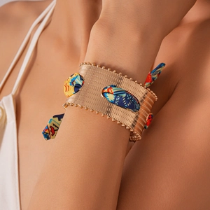 Detail of wide gold cuff bracelet featuring bohemian silk fabric inlay and beaded edges