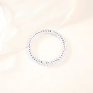 Detailed macro of shiny silver spiral hair tie with smooth metallic finish and elastic coils