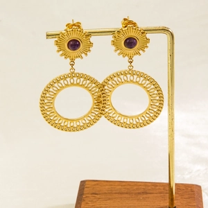 Detail of vintage gold drop earrings with purple stones on a professional display stand