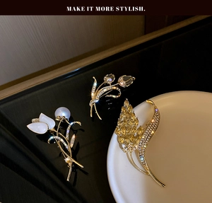 Détail de broches épis de blé et tulipes dorées avec pierres précieuses et perles sur miroir