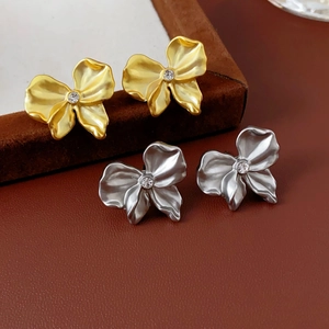 Detailed macro view of matte gold and silver petal earrings with sparkling diamonds