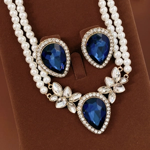 Détail de parure bijoux vintage avec pierres bleues et perles sur présentoir en velours