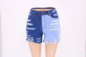 Detail of high-waisted patchwork denim shorts with distressed holes and frayed hems