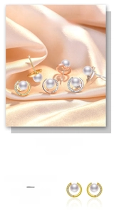 Close-up of elegant pearl stud earrings with zircon inlay on champagne silk fabric