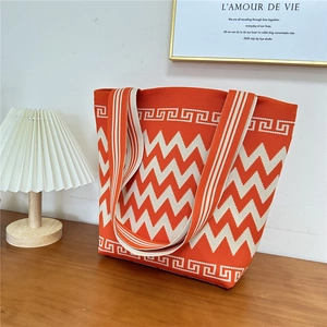 Detail of orange chevron knit tote bag with thick woven texture on a wooden table