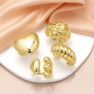 Set of four 18k gold plated heart and textured rings on a white plate with pink silk