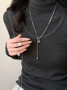 Detailed view of silver Y-shaped asymmetric star necklace on a textured grey sweater