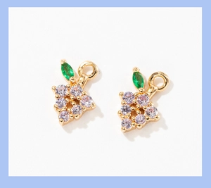 Macro view of gold-plated berry charm with micro-pave zircons and green leaf details
