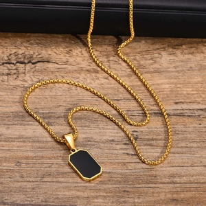 Detail shot of a golden stainless steel chain with a black rectangular pendant on wood