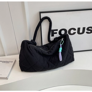 Detail of black quilted puffer tote bag featuring a bicolor purple and mint green charm
