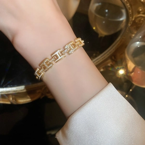 Gros plan d'un bracelet doré à maillons géométriques avec émail blanc et zircons brillants