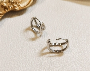 Macro shot of S925 sterling silver double hoop earrings on a textured cream leather surface