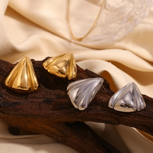 Macro shot of geometric gold and silver triangle stud earrings on natural wood texture