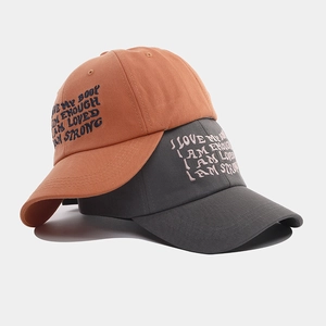 Detail of soft cotton twill fabric and embroidered motivational slogans on baseball caps