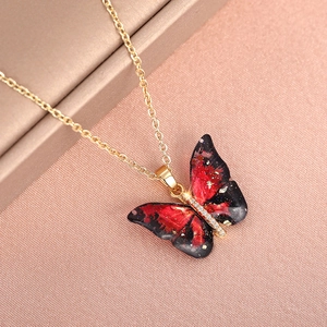Macro shot of gold butterfly pendant with red gradient resin and inlaid crystals