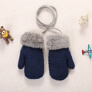 Close-up of navy blue double-layer knitted baby mittens with faux fur trim and neck cord