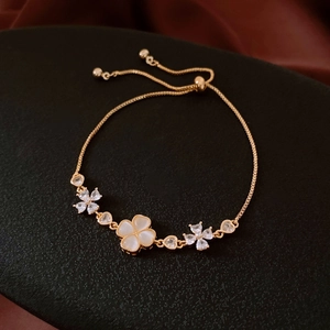 Macro shot of 18K gold flower bracelet with opal clover and adjustable slide clasp