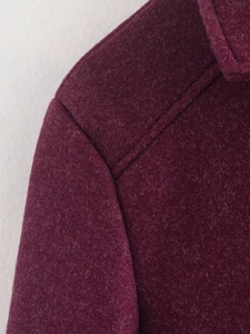 Detail shot of deep purple wool jacket showing premium texture and shoulder stitching