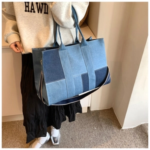 Detail view of large denim tote bag featuring multi-tone patchwork and contrast stitching