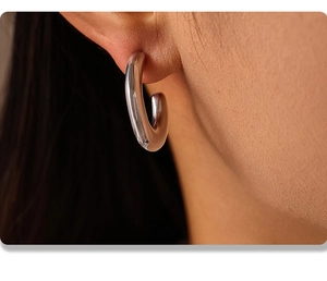 Macro shot of silver minimalist chunky C-shaped hoop earrings worn by a model