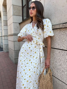 Close-up of white floral cotton dress showing wrap V-neck and puff sleeves detail