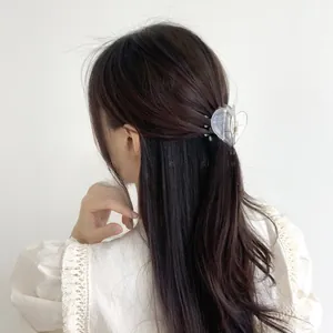 Detail view of heart-shaped transparent hair claw clip styled on brunette hair