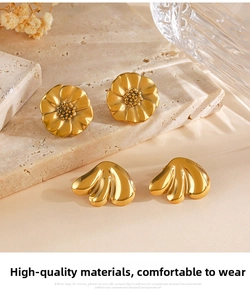 Detail of vintage gold floral stud earrings and shell-shaped titanium steel jewelry