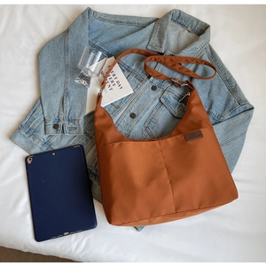 Detailed shot of a caramel brown crossbody canvas tote bag with adjustable strap and zip