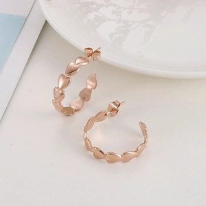 Close-up of rose gold heart-shaped hoop earrings on a minimalist white tray