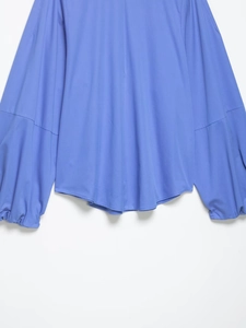 Détail d'une chemise en popeline bleue avec manches ballon et poignets élastiques