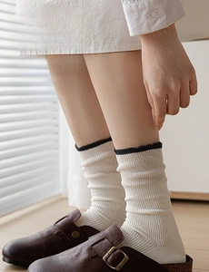 Detailed macro view of cream-colored ribbed crew socks with elegant black lace trim