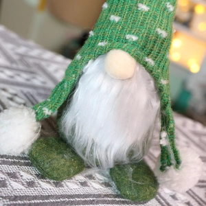 Gnomo di Natale in maglia verde con barba lunga e sfondo con luci calde del festival