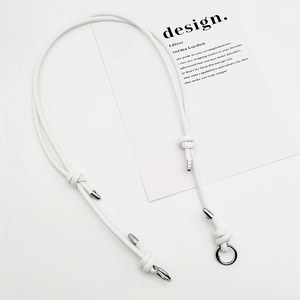 Detail shot of a white adjustable leather bag strap with polished silver metal clasps