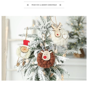 Detail von Schneemann- und Rentier-Filzanhängern an einem verschneiten Weihnachtsbaum