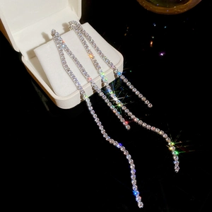 Macro shot of long silver tassel earrings with sparkling cubic zirconia on a white jewelry box