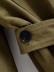 Detail view of army green jacket sleeve with black button and twill fabric texture