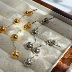 Detail of 18K gold and silver plated triple ball drop earrings on velvet display