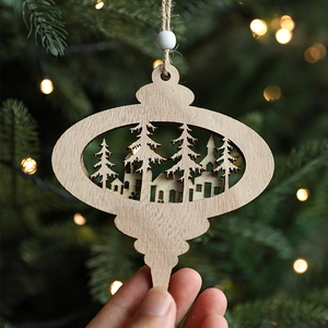 Wooden Christmas ornament featuring laser-cut forest house scenery with warm festive lighting