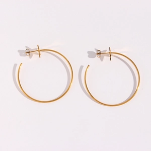 Macro detail of large gold stainless steel hoop earrings with glossy polished finish