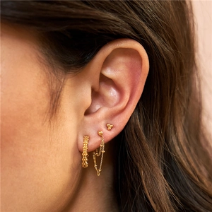 Close-up of gold flower stud, chain earring and beaded ear cuff set on model