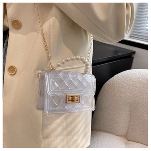 Detail of transparent PVC mini bag with quilted texture and faux pearl handle