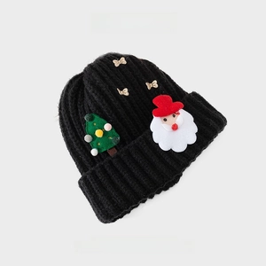 Detailed knit texture of a black Christmas beanie with Santa and tree patches