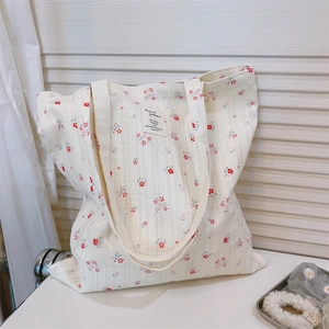 Detail of floral tote bag with blue and red patterns on textured white cotton canvas