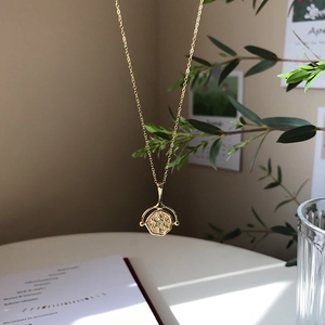 Detail shot of a spinning 18K gold coin pendant with texture and sparkling rhinestone