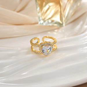 Close-up of gold heart-shaped ring with micro-pave crystals on wavy white surface