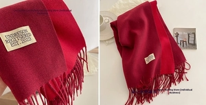 Detail of red cashmere-feel scarf featuring double-sided color and elegant fringe design
