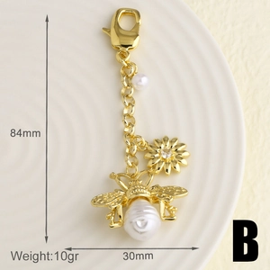 Détails d'un porte-clés abeille doré avec perles et pendentif marguerite, dimensions 84mm